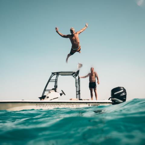 Photo of man jumping from boat to the sea